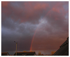 Rood gekleurde regenboog, binnen de boog is het licht ook rood. dit verschijnssle komt voor bij zeer laag staande zon